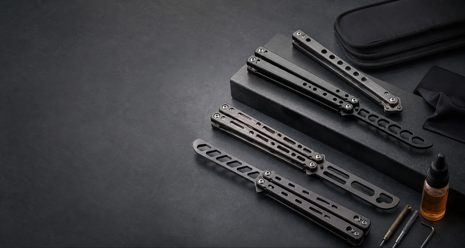 Balisong trainer practice tools on a graphite workbench